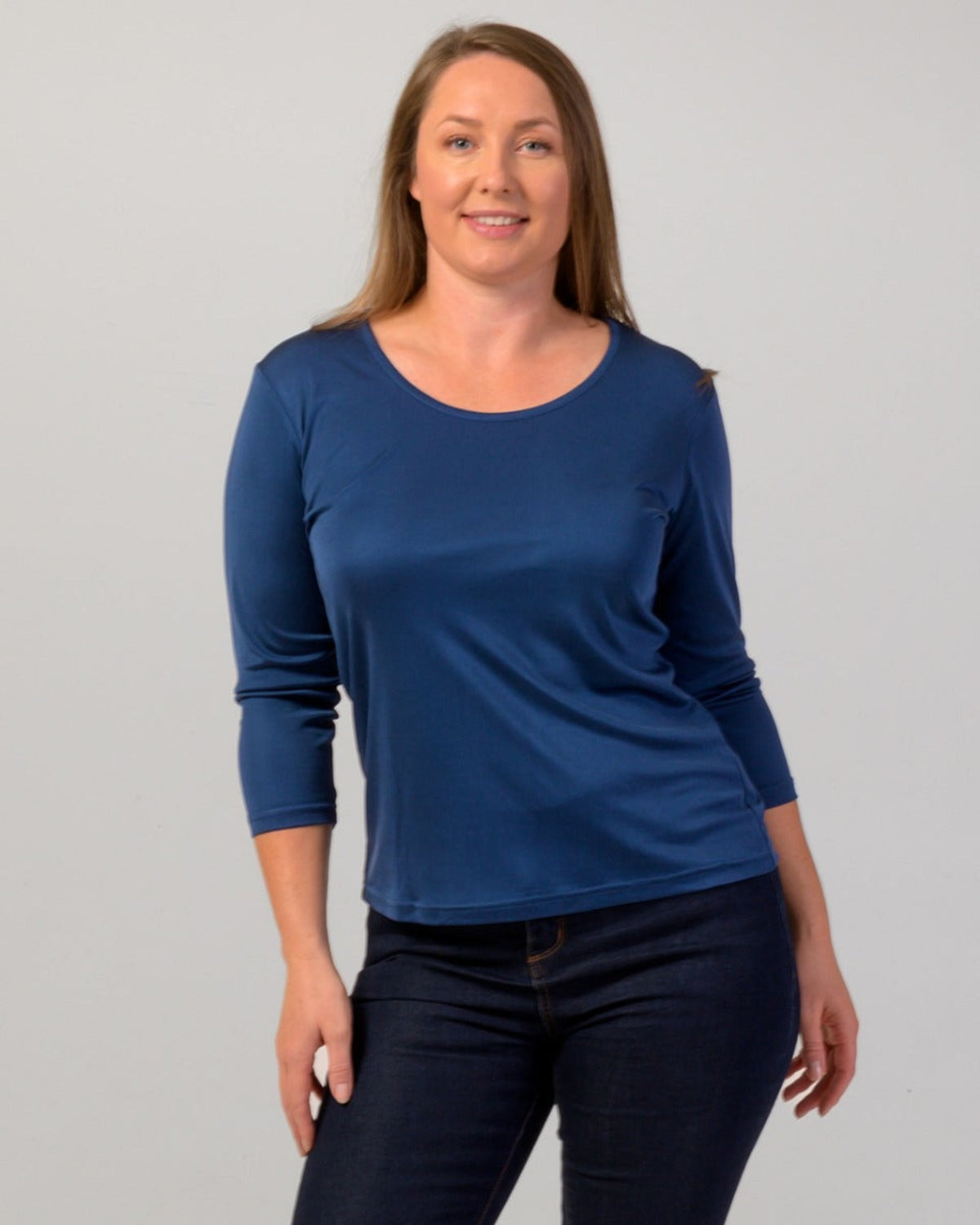Woman wearing a silk blue long-sleeve top against a gray background