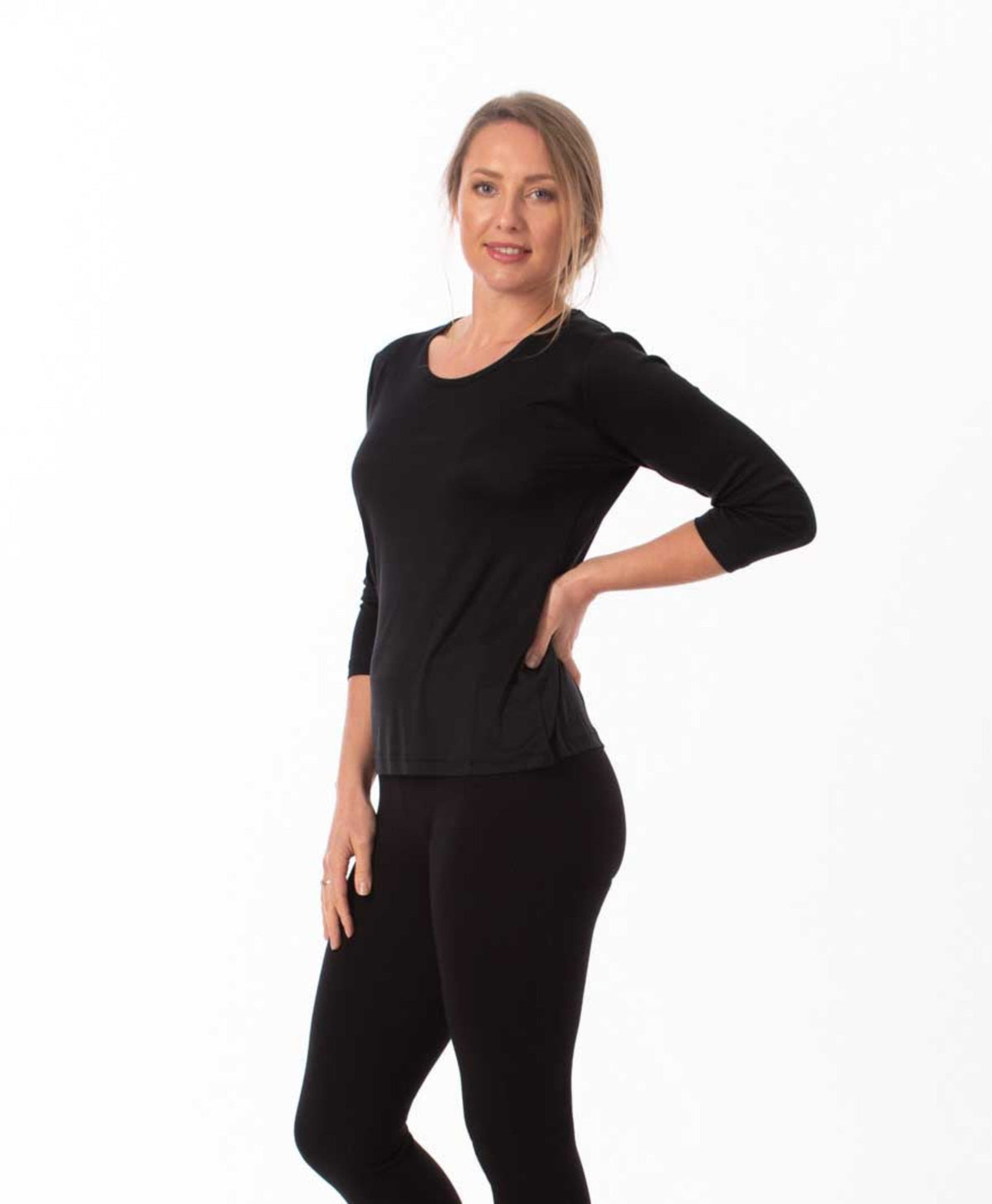 Woman wearing a silk black long-sleeve top and black leggings on a white background