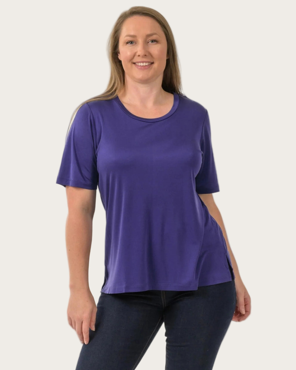 Woman wearing a silk  purple t-shirt and black pants on a white background