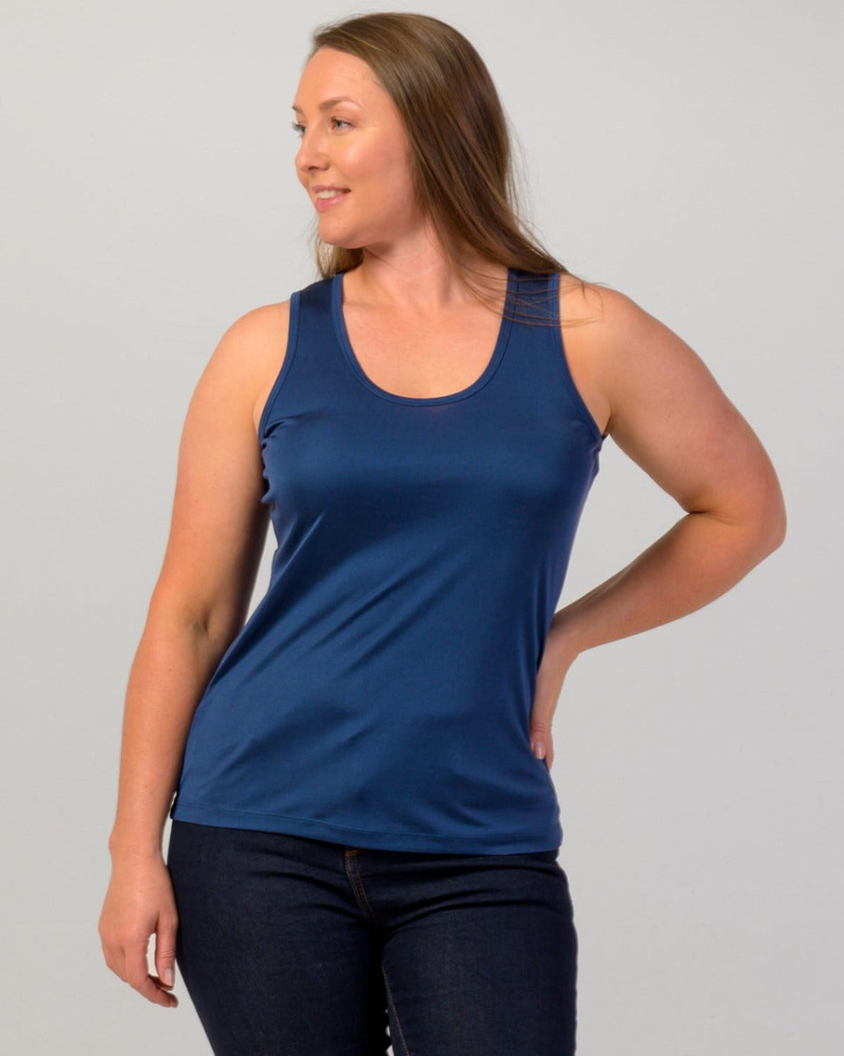 Woman wearing a silk blue tank top against a gray background