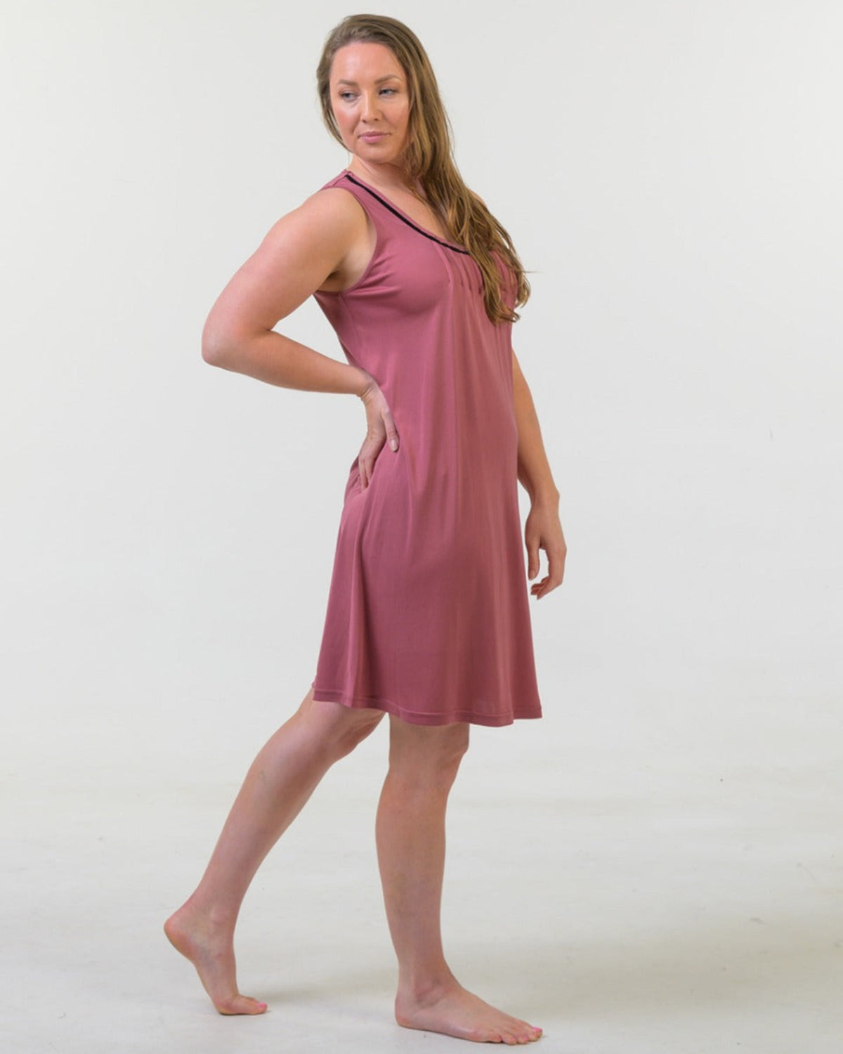 Woman wearing a silk mauve sleeveless dress against a white background