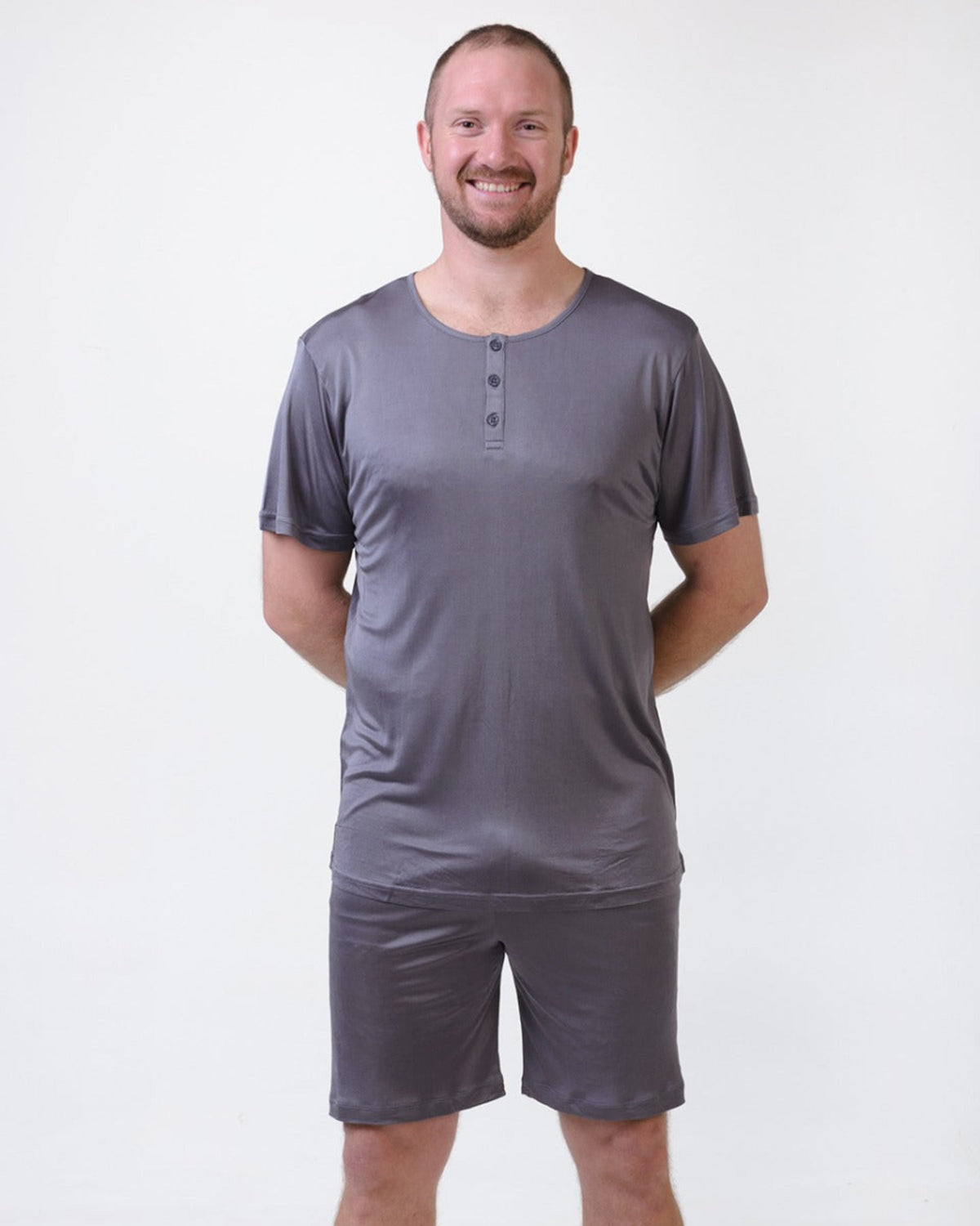 Man wearing a silk gray henley shirt and shorts set on a white background