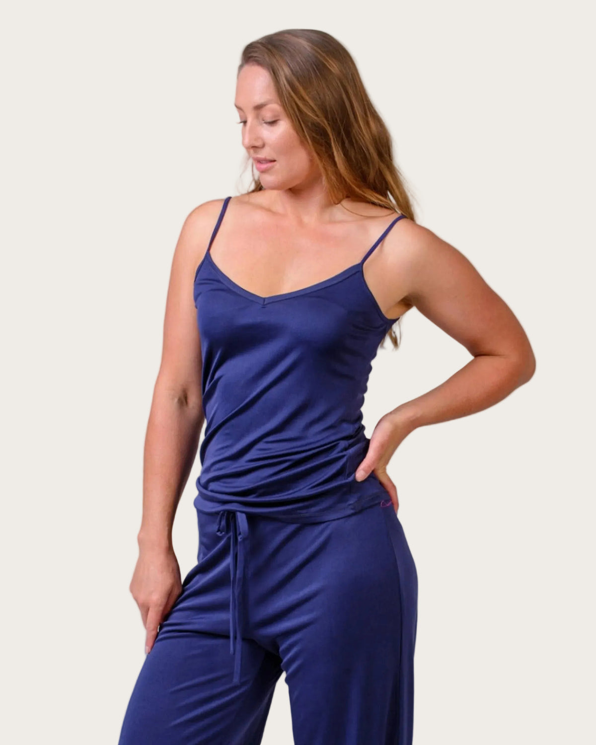 Woman wearing a blue silk camisole  against a white background