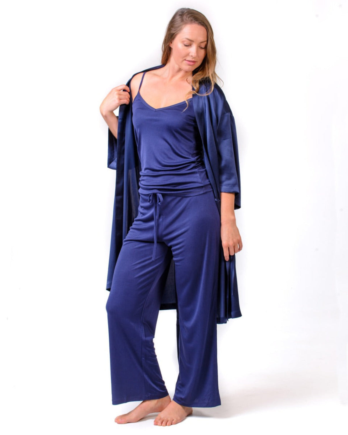 Woman wearing a silk blue satin loungewear set with a matching robe o