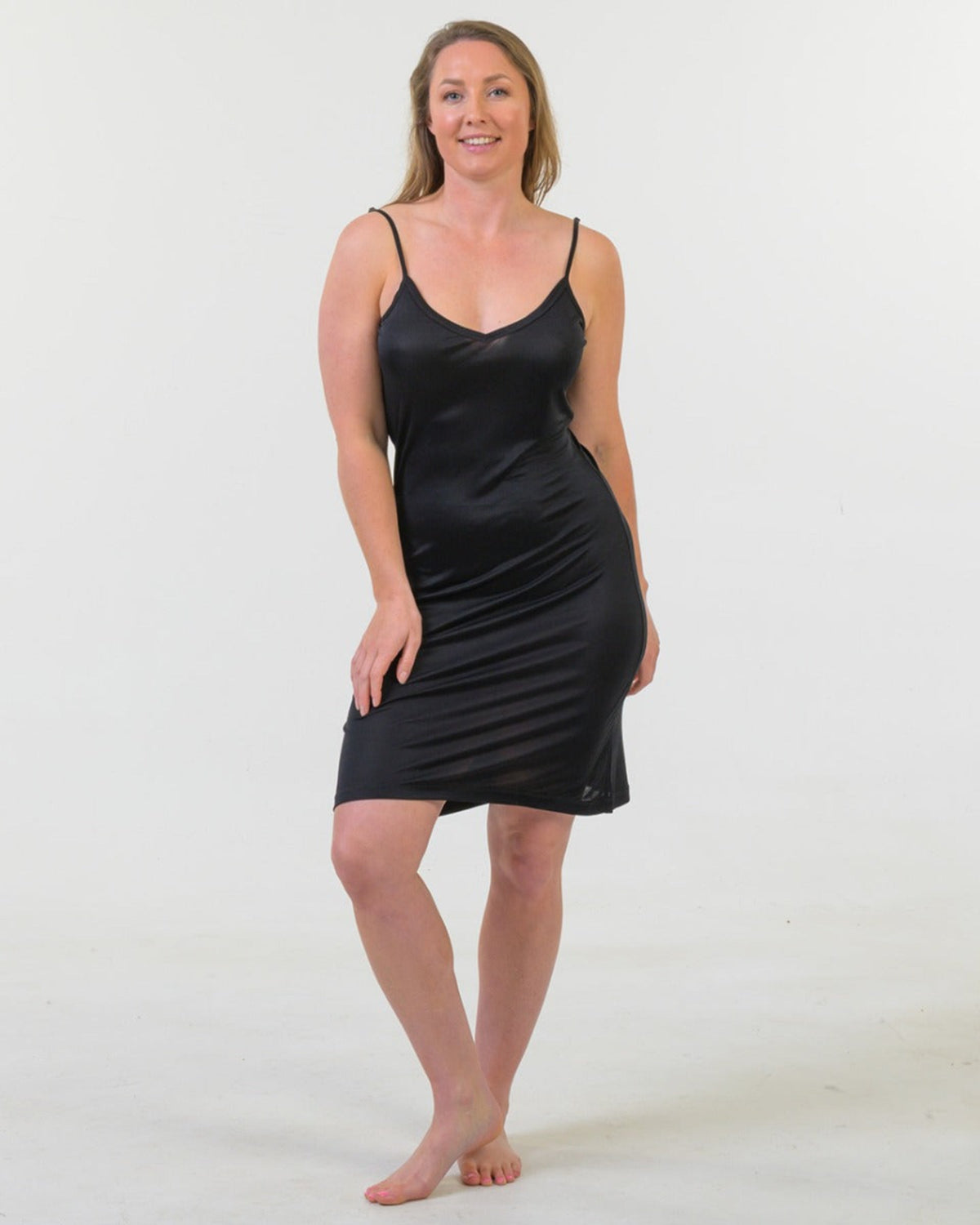 Woman wearing a silk black slip dress against a white background