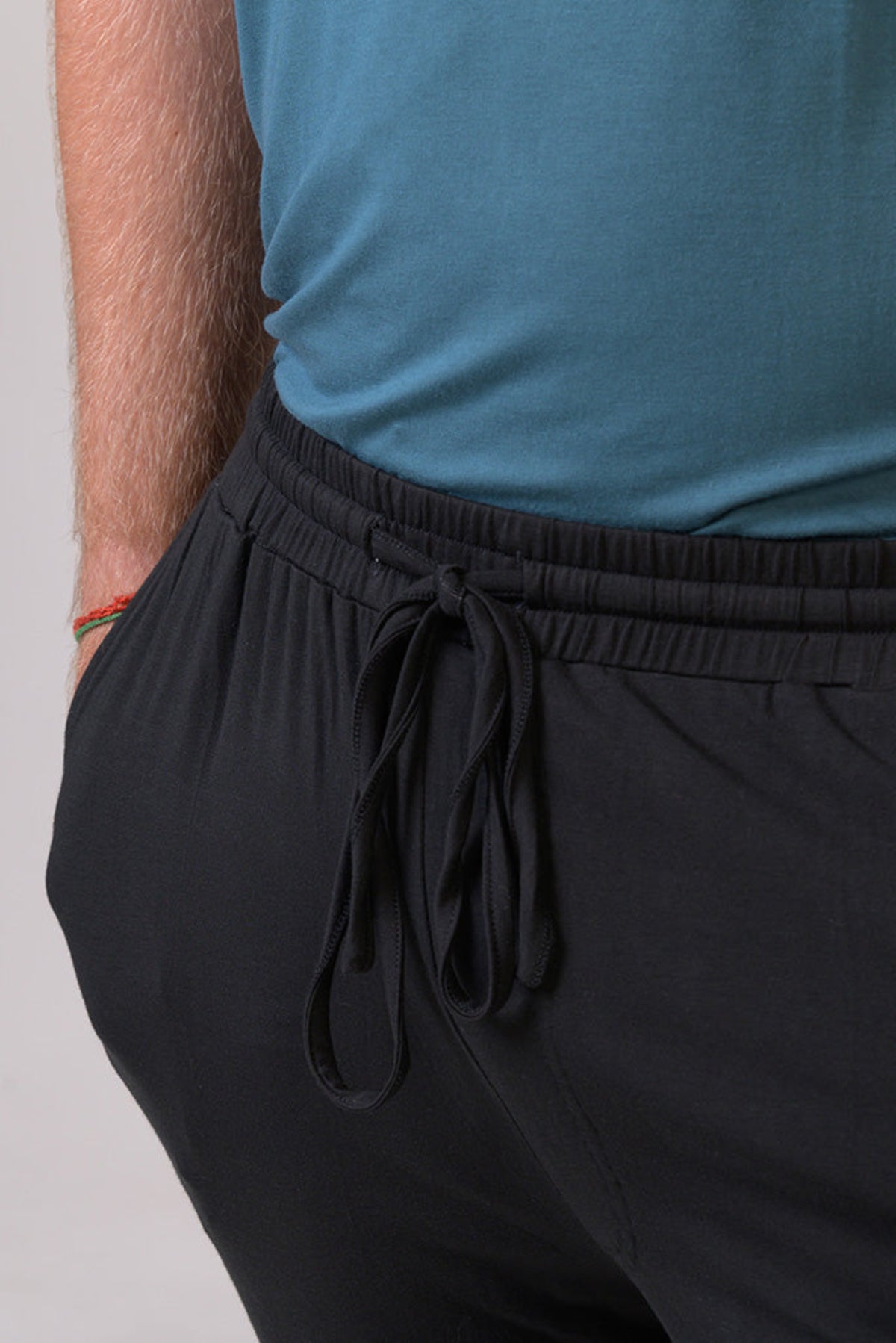 Person wearing black pants with a blue top on a plain background