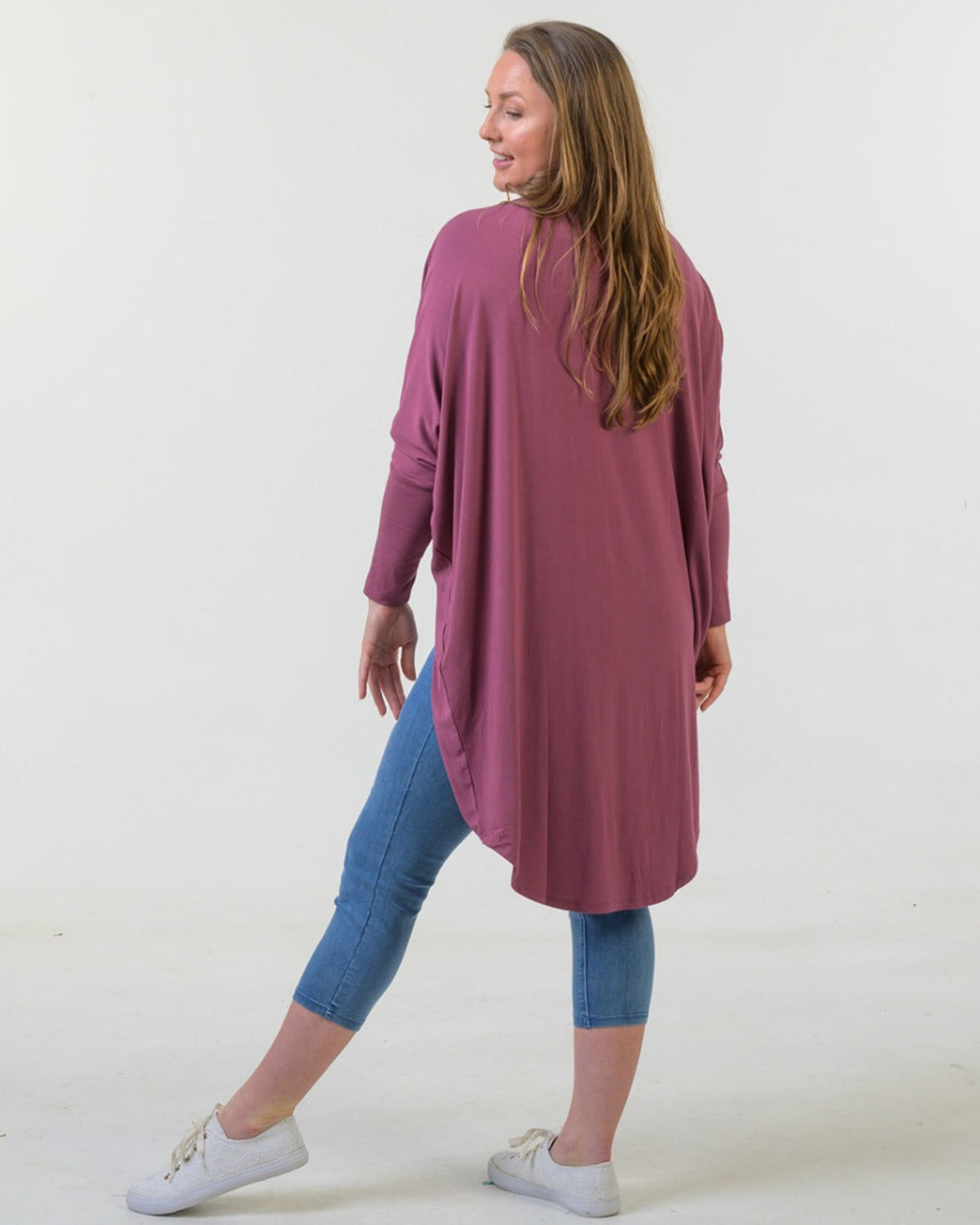 Woman bamboo cocoon wearing a long mauve cardigan over blue jeans on a white background