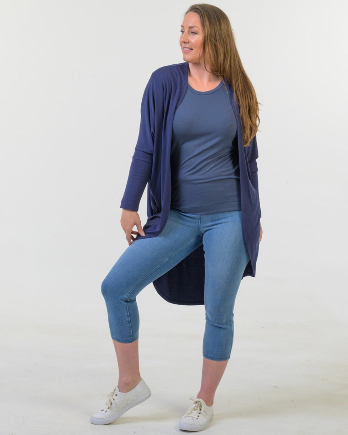 Woman bamboo cocoon wearing a blue cardigan, blue top, and jeans on a white background