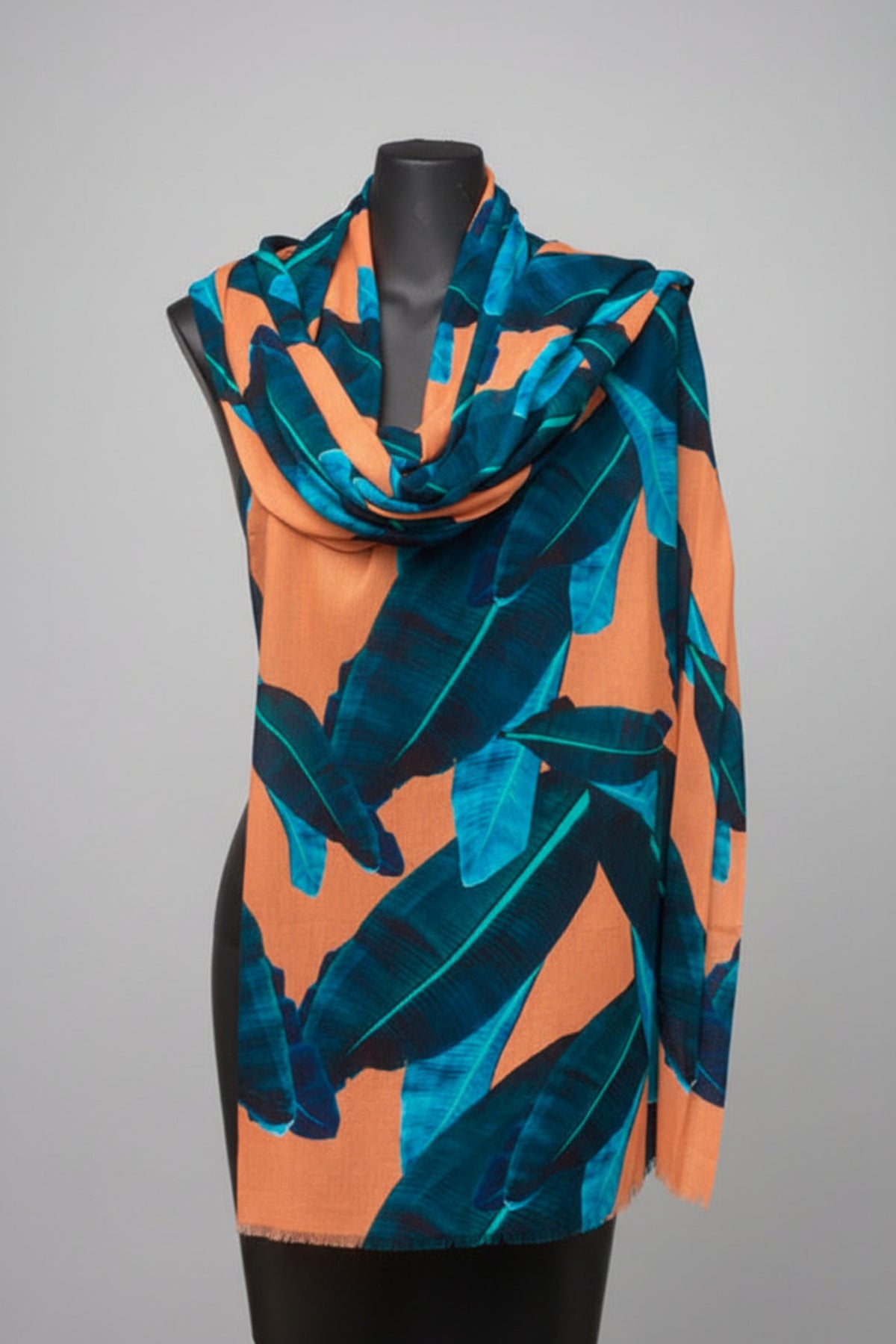 Mannequin wearing a scarf with blue leaf pattern on an orange background