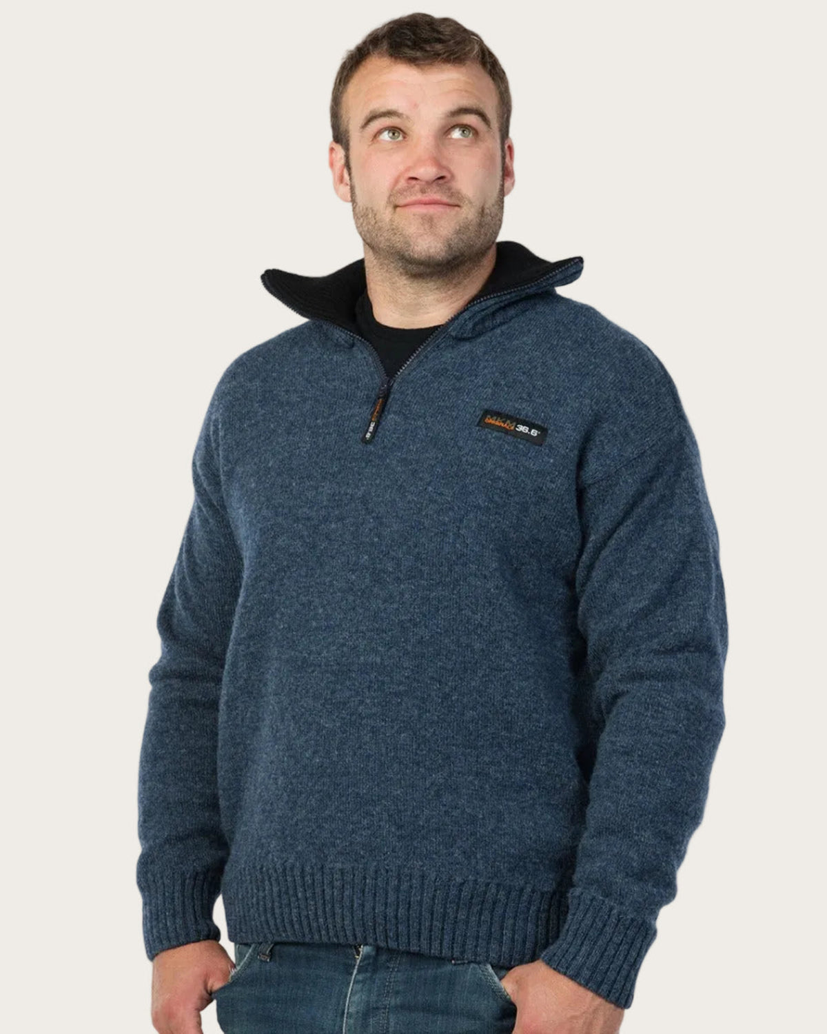 Man wearing a blue sweater with a brand logo on a white background