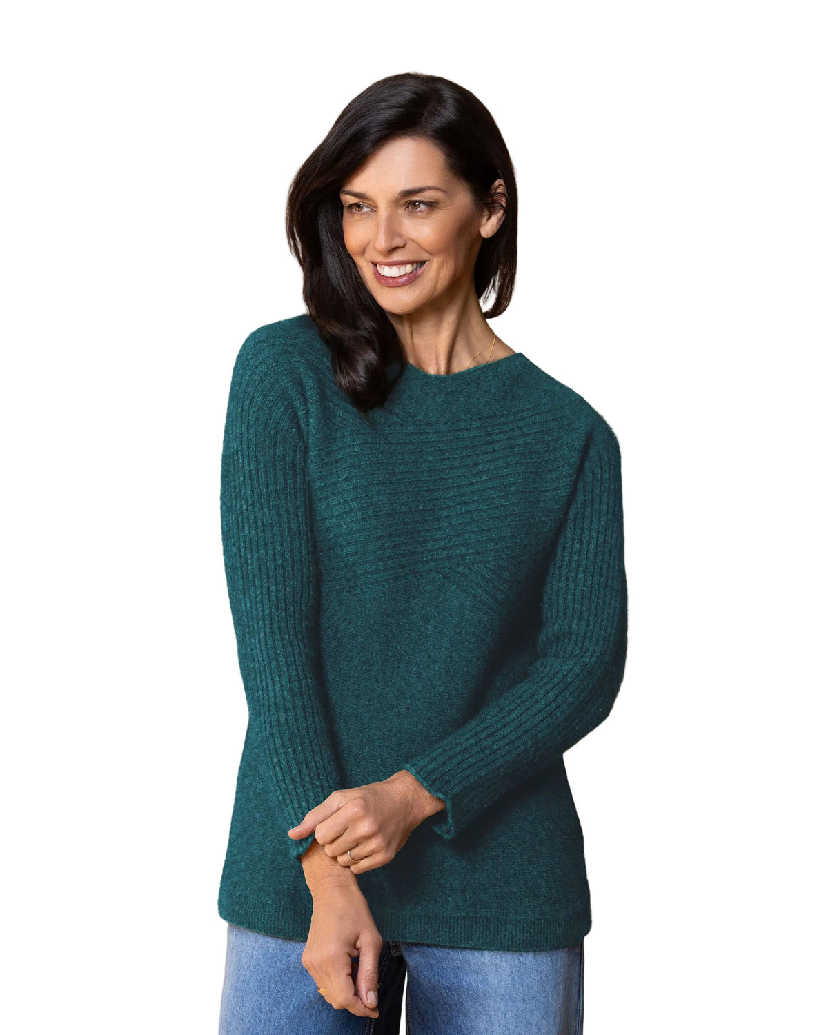 A woman wearing a dark teal green ribbed possum merino knit sweater and blue jeans, standing against a solid light gray background.