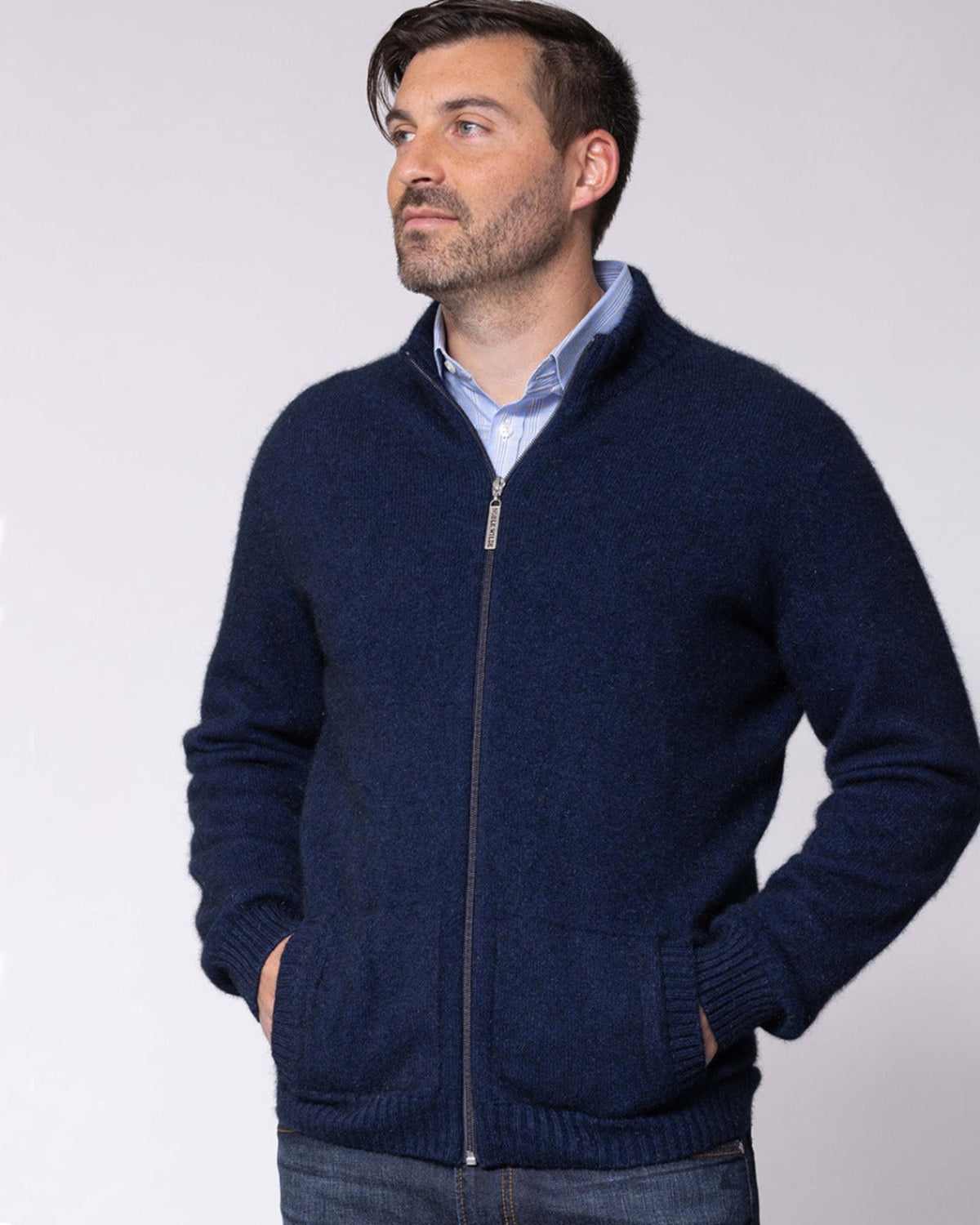 Possum Merino Man wearing a navy blue zip-up sweater against a white background