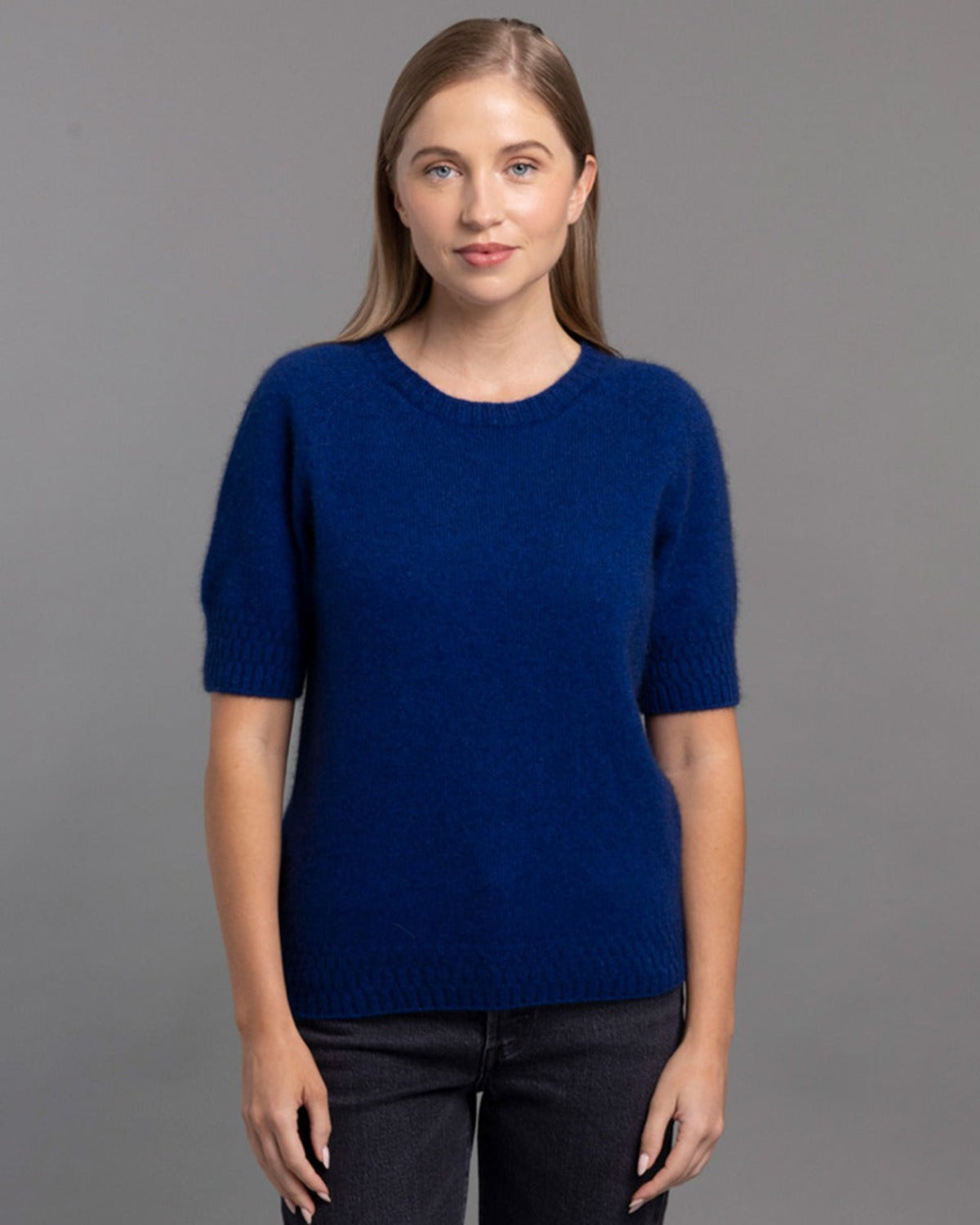 Possum merino Woman wearing a blue sweater against a gray background