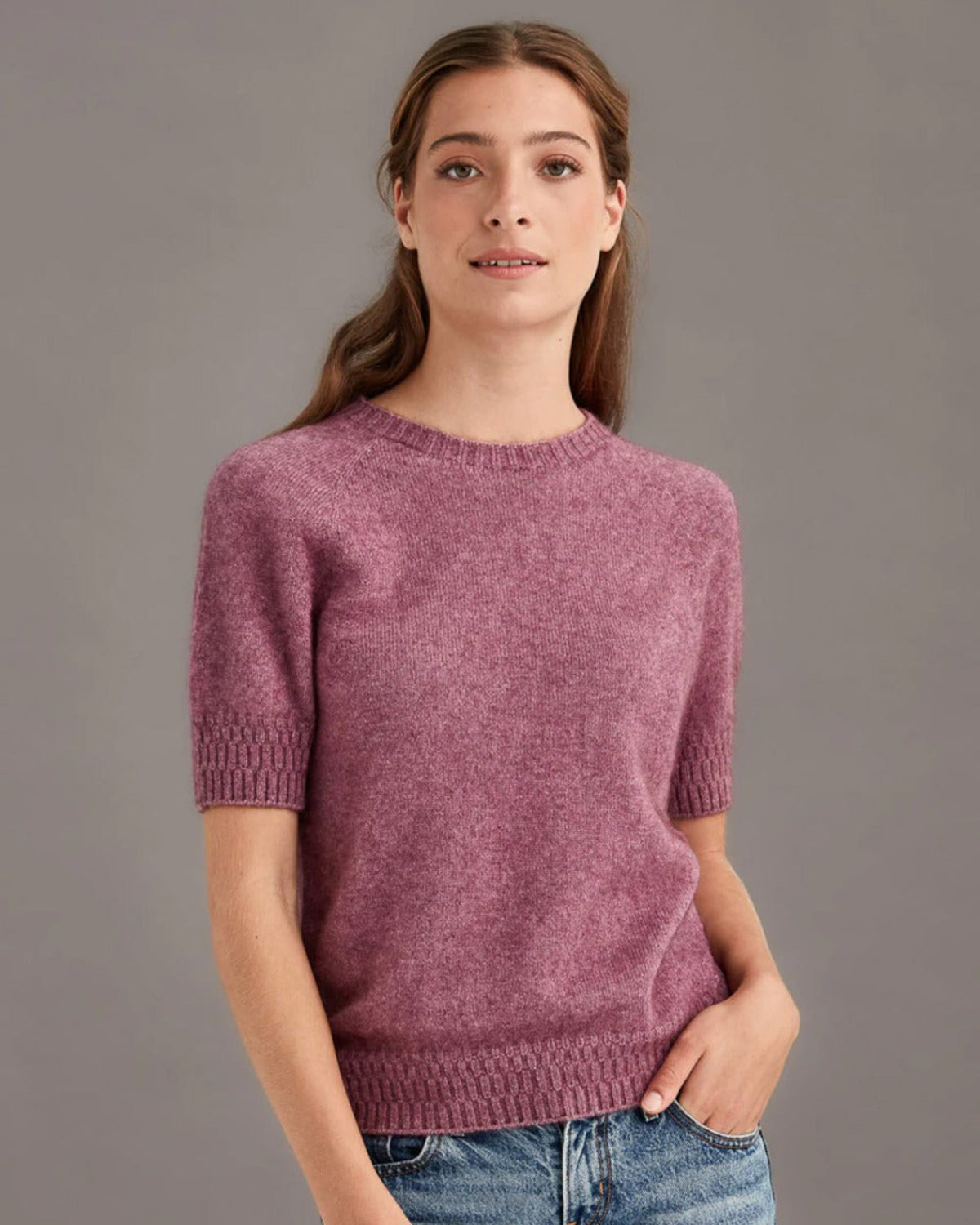 Possum merino Woman wearing a pink sweater against a gray background