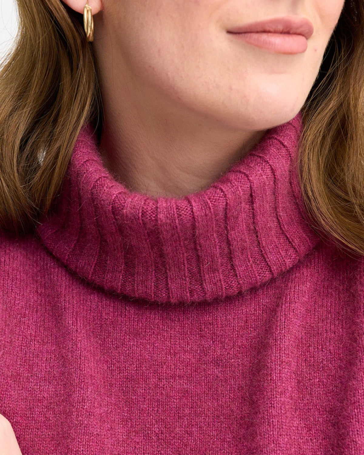 possum merino Close-up of a person wearing a magenta turtleneck sweater with a neutral background