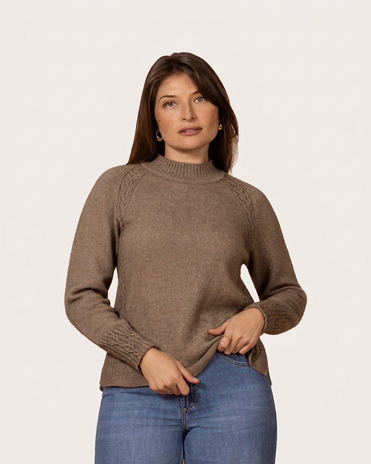 Women in a beige coloured possum merino sweater with cable detailing at shoulder and cuffs and a low mock turtle neck.