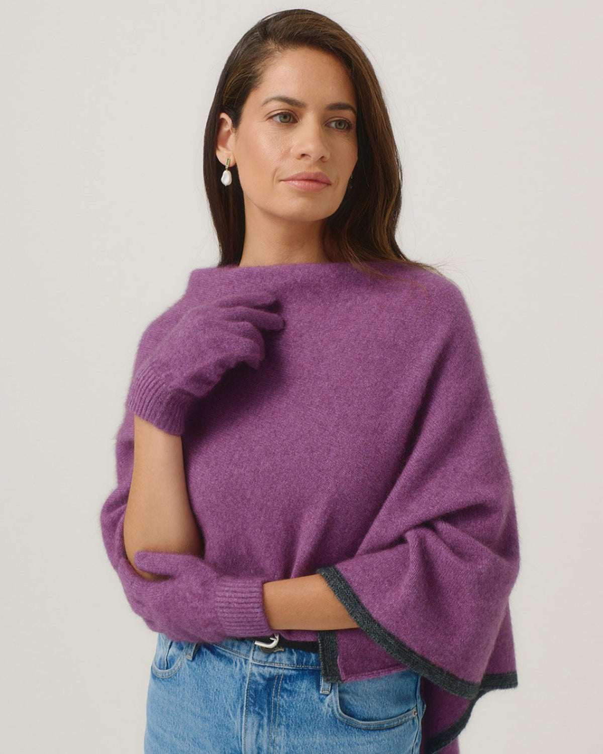 Possum merino Woman wearing a purple sweater and blue jeans on a plain background