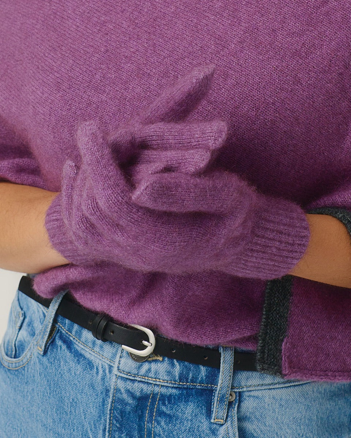 Possum merino Purple sweater and gloves worn by a person with blue jeans.