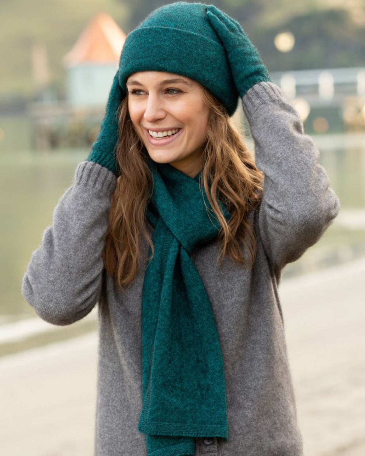 possum merino Woman wearing a green beanie and scarf with a gray coat outdoors.
