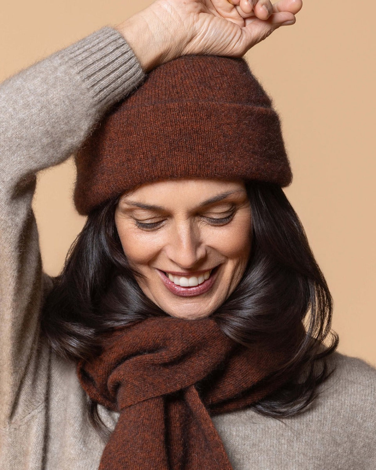 possum merino Woman wearing a brown knitted hat and scarf against a beige background