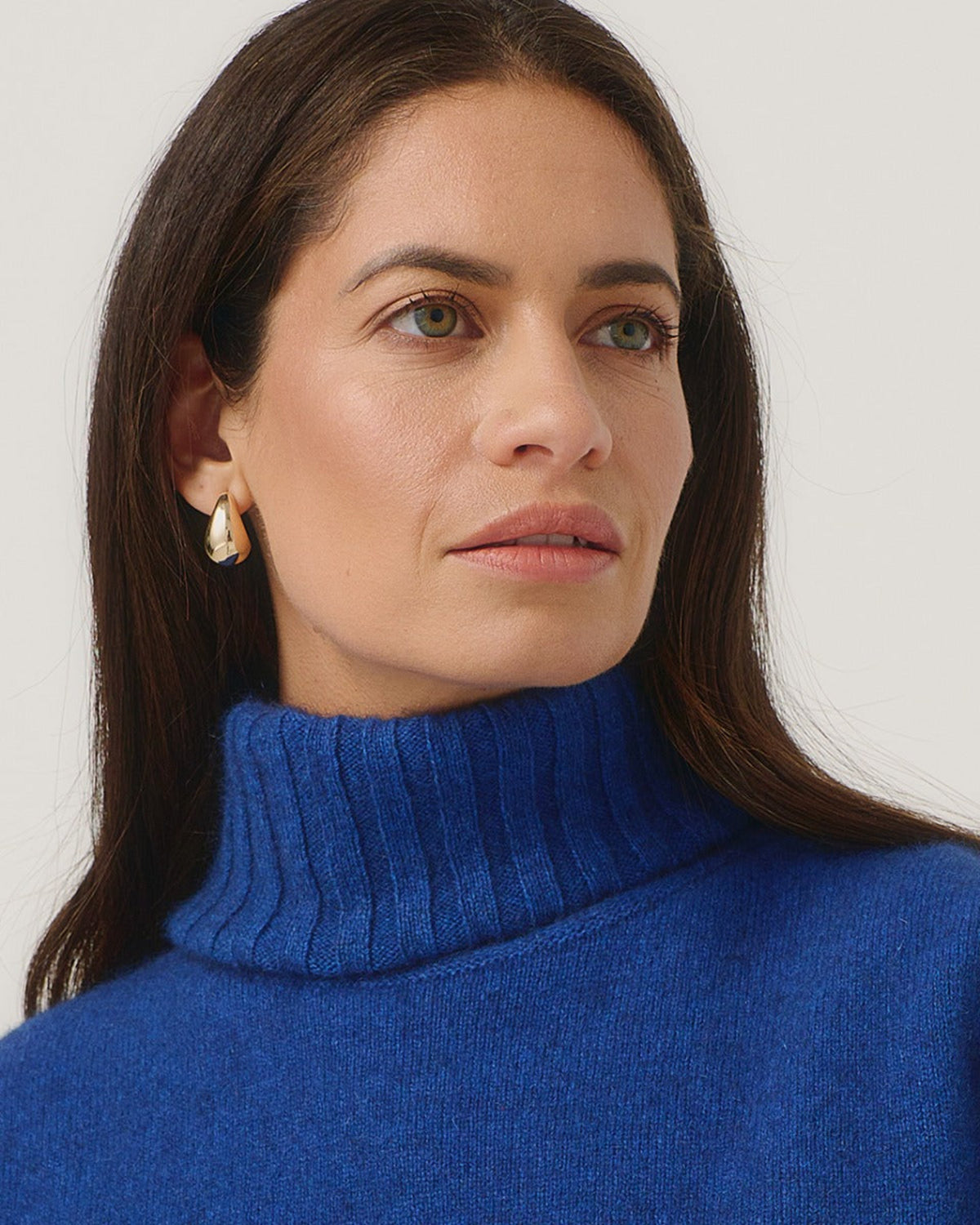 possum merino Woman wearing a blue turtleneck sweater against a white background