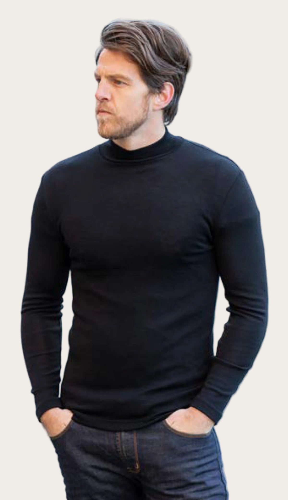 Man wearing a merino black turtleneck sweater standing by a body of water.