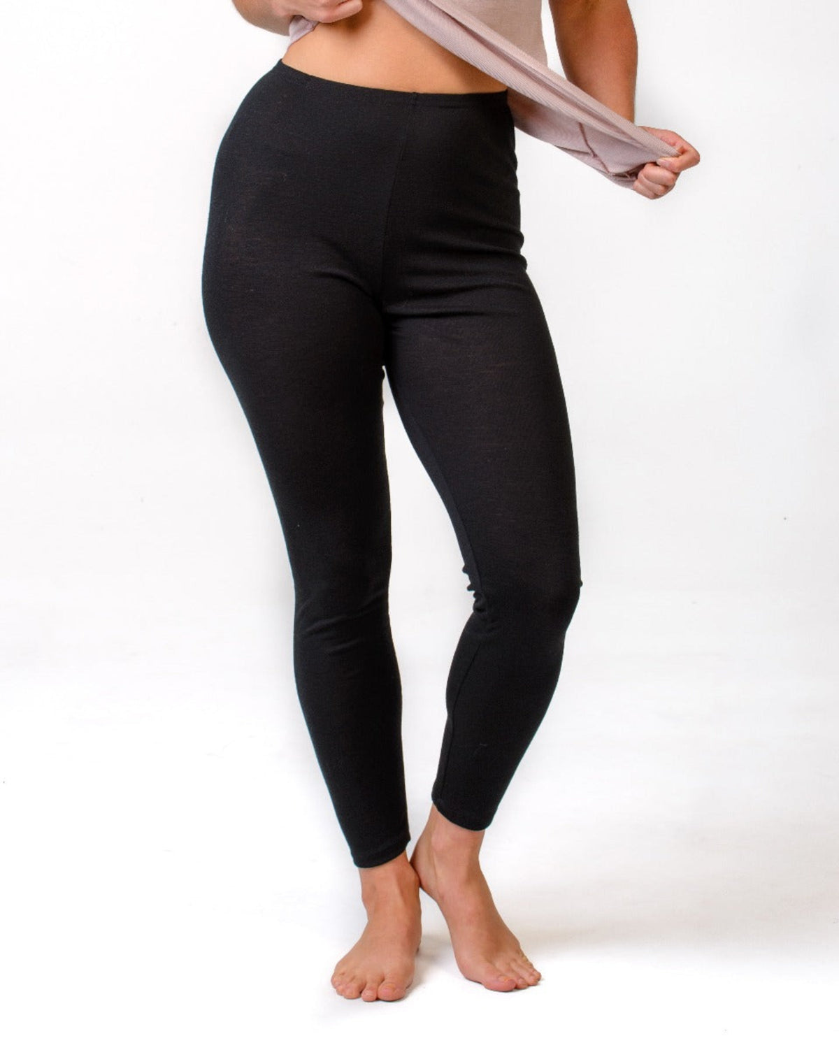 Person wearing merino  black leggings on a white background