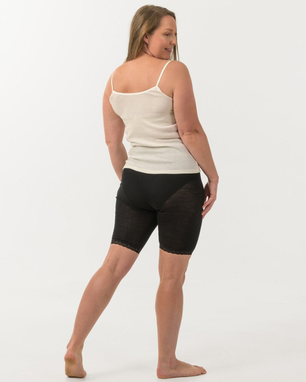 Merino Woman wearing a beige tank top and black shorts on a white background