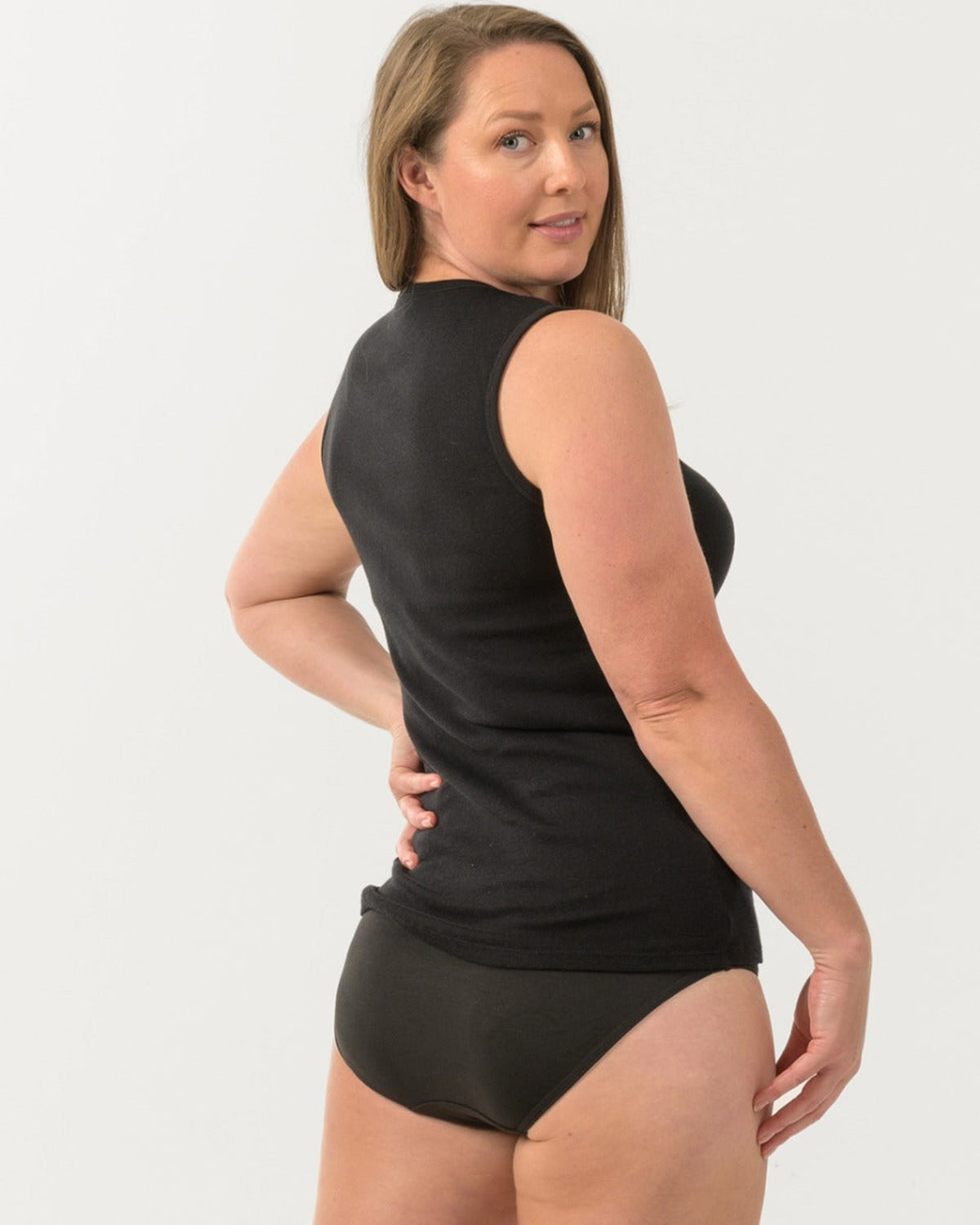 Woman wearing a black merino cotton sleeveless top and black underwear on a white background