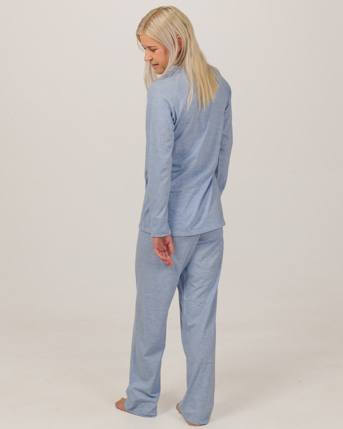 Woman wearing a merino cotton light blue pajama set against a plain background