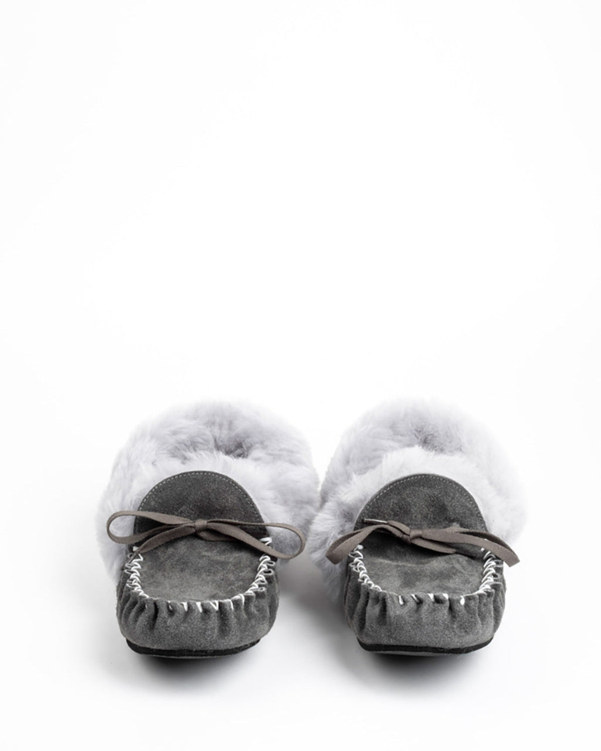 A pair of gray suede moccasin slippers with fluffy white faux fur sheepskin and dark brown leather bows, shown from a top-down view on a white background.