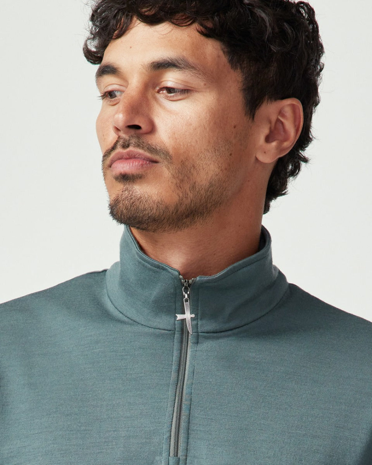 Merino Man wearing a teal zip-up sweatshirt against a light gray background