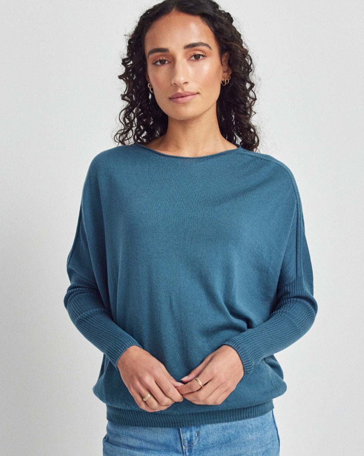 Woman wearing a merino blue sweater on a light gray background