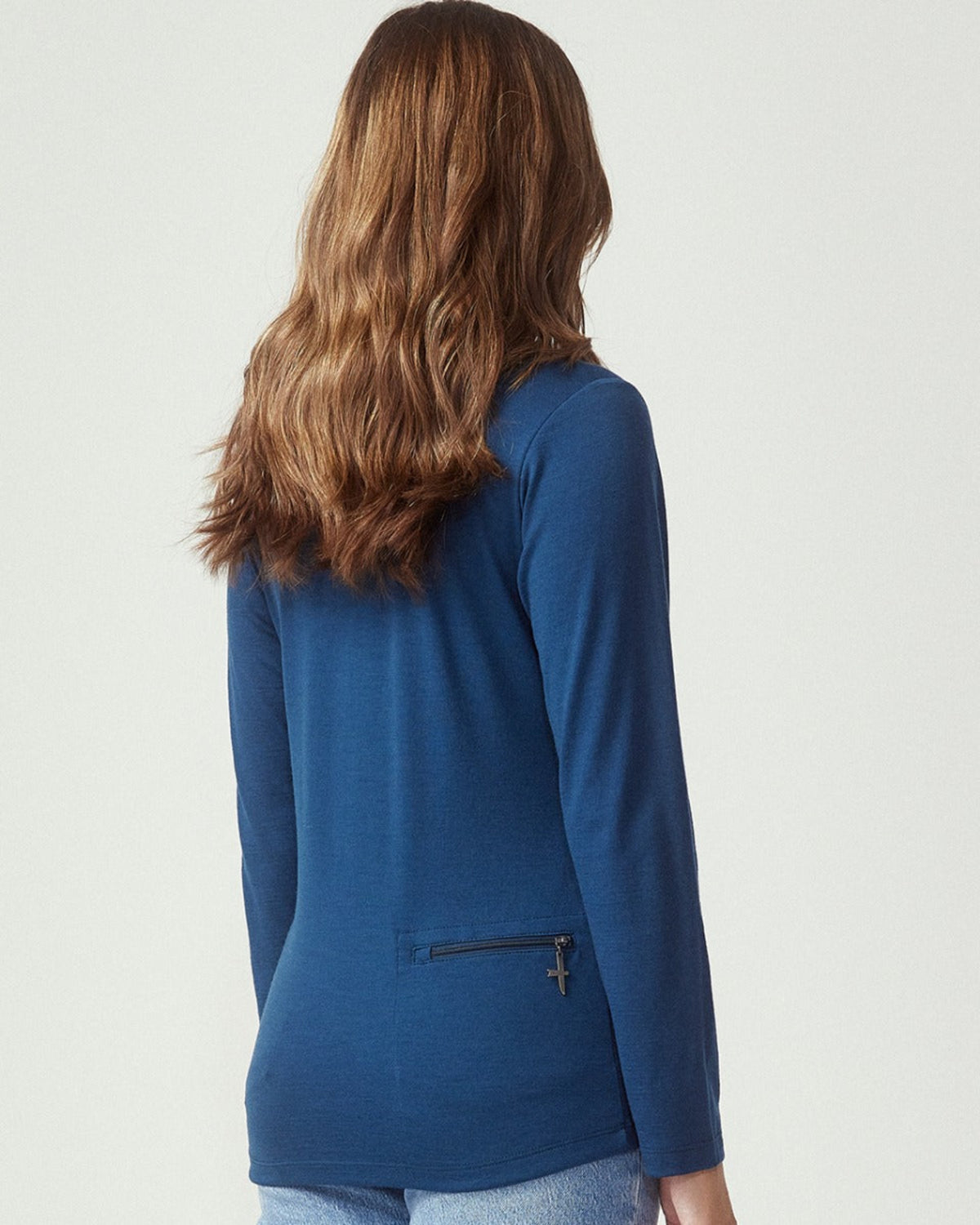 Person wearing a merino blue jacket with a plain background