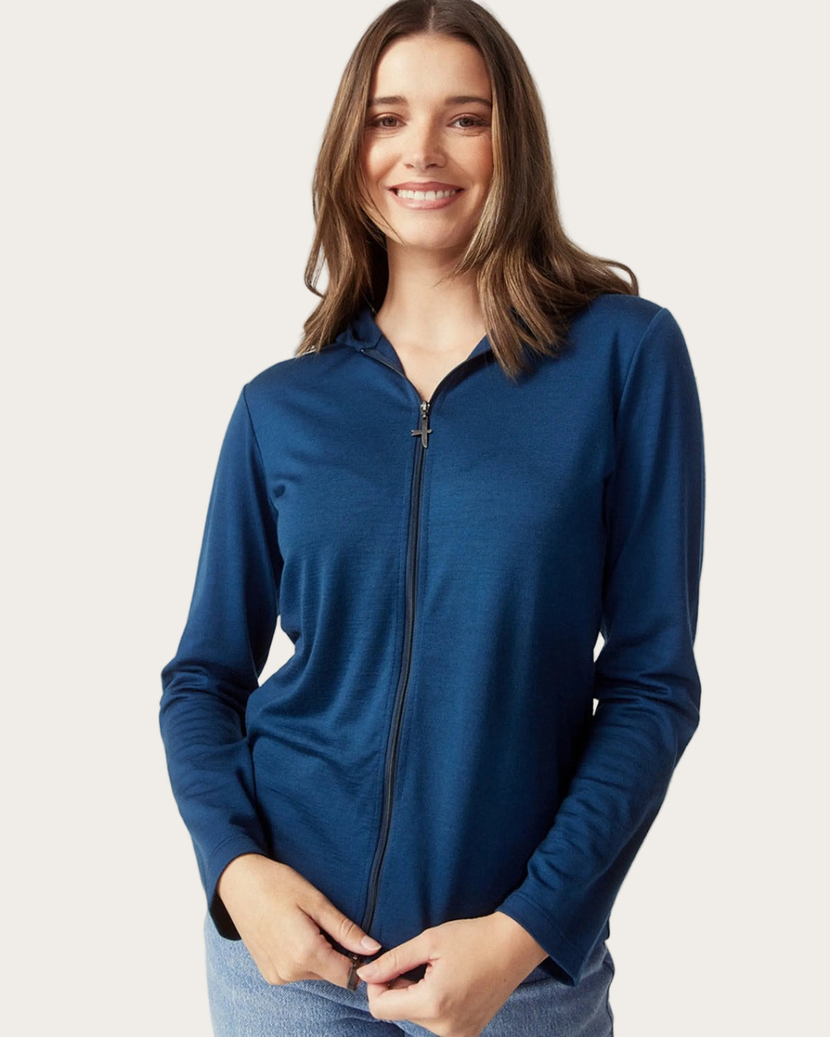 Woman wearing a merino blue long-sleeve top with a zipper on a light gray background