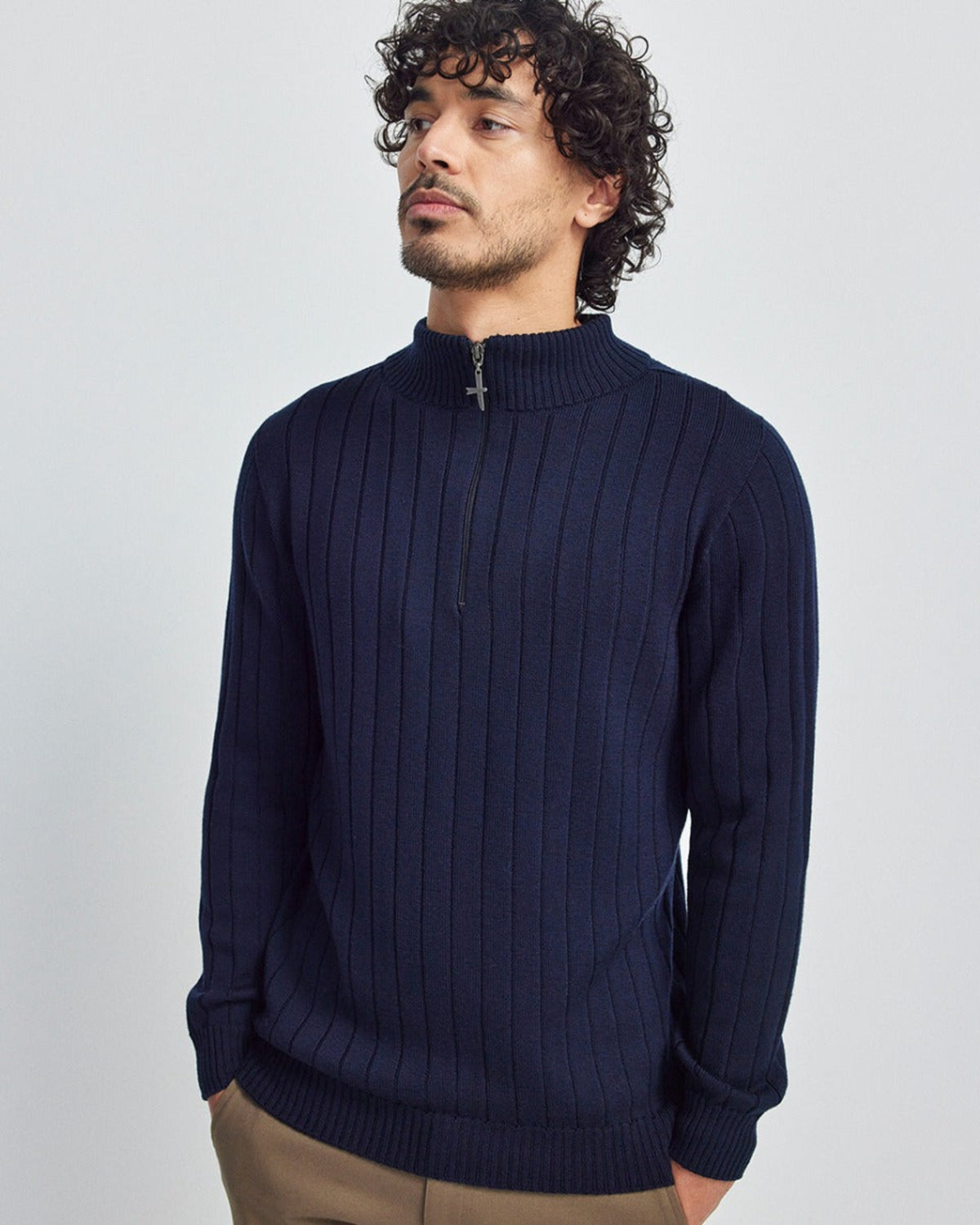 Man wearing a merino navy blue ribbed sweater against a light gray background