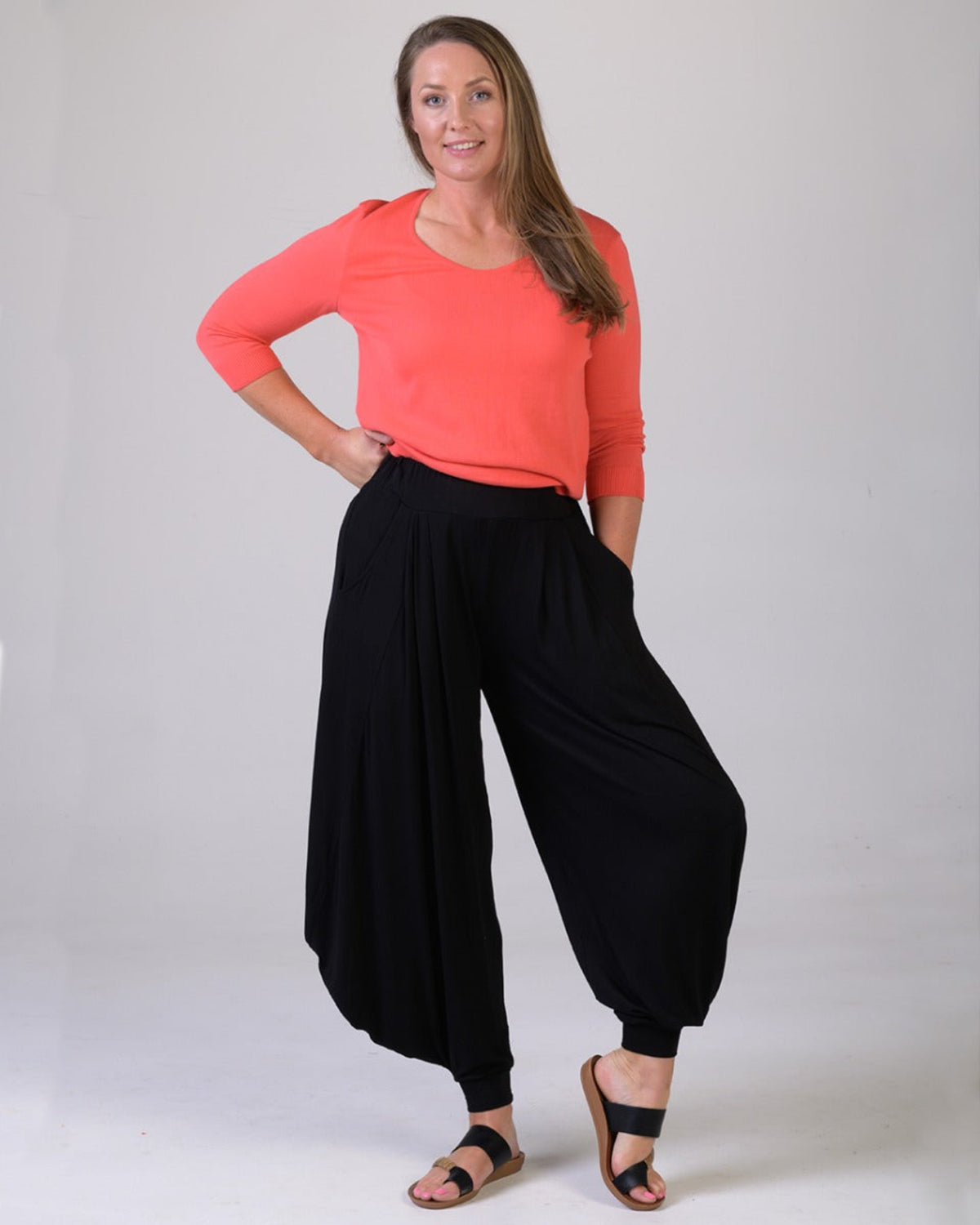 Viscoe Woman wearing a coral top and black wide-leg pants on a plain background