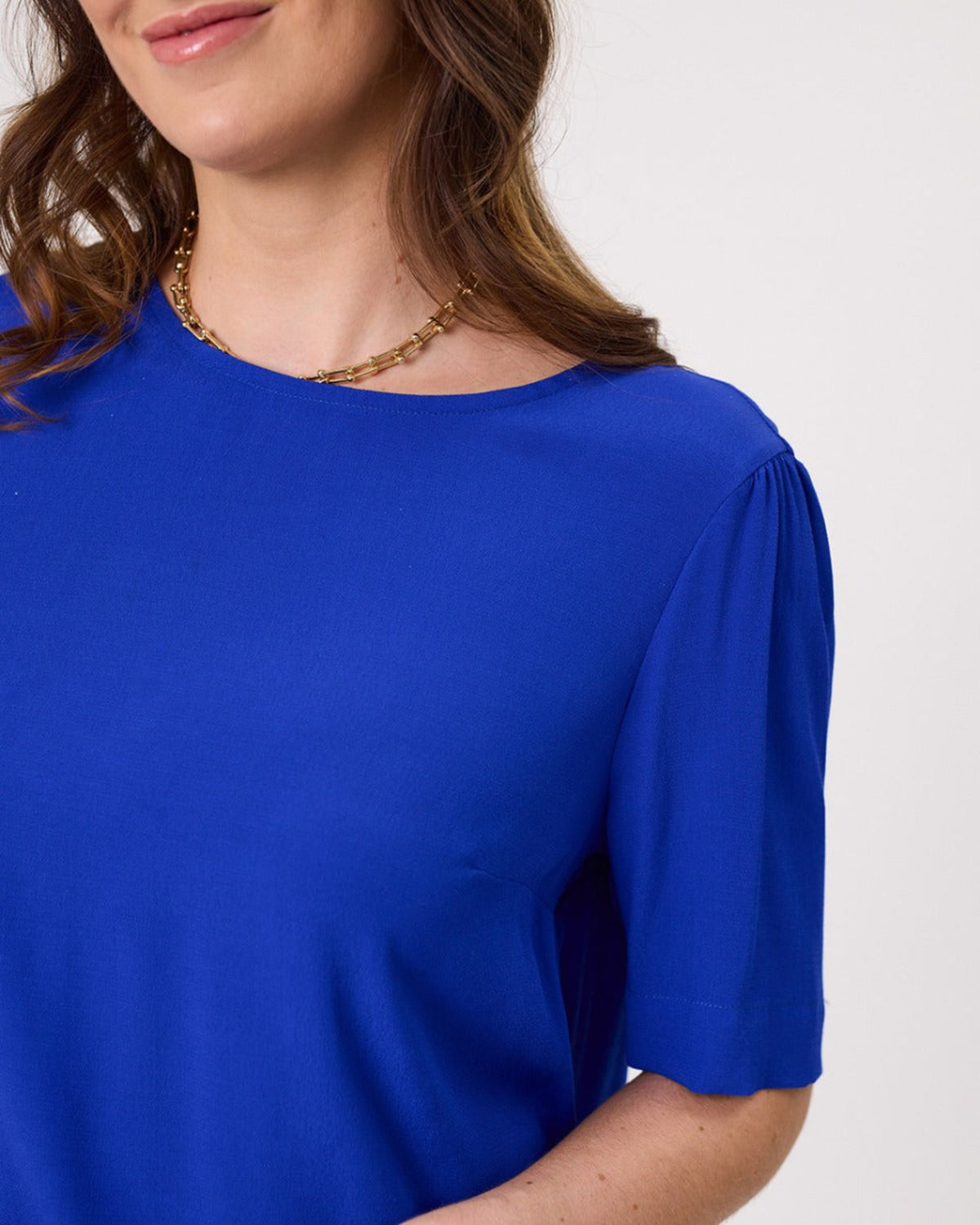 Blue top worn by a person on a white background