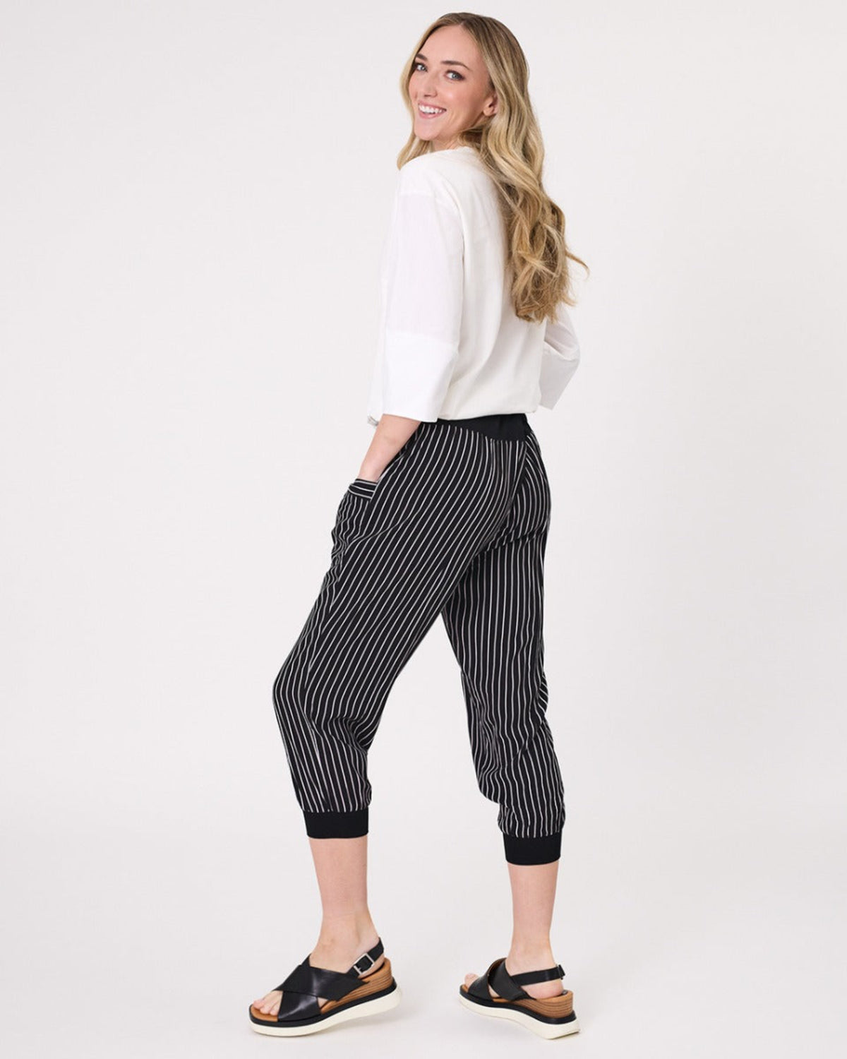 Viscoe Woman wearing a white top and black striped pants on a white background