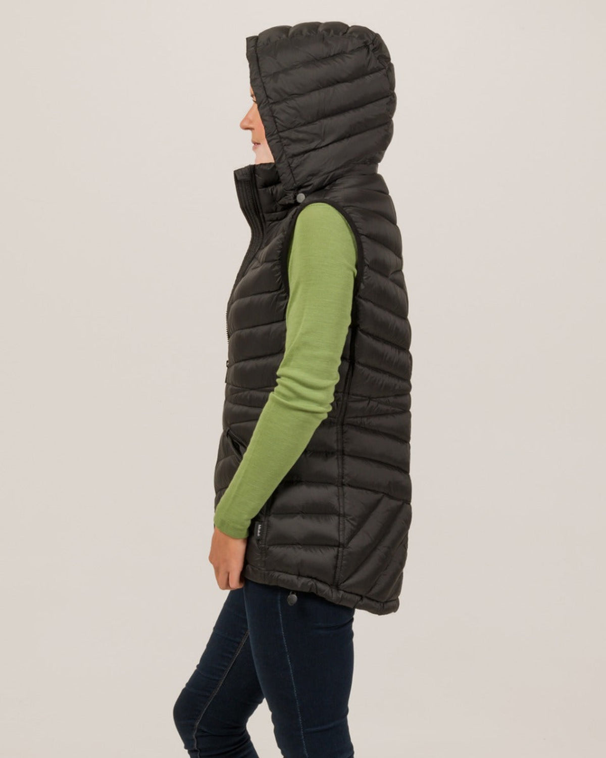women  black puffer vest over a green shirt on a plain background