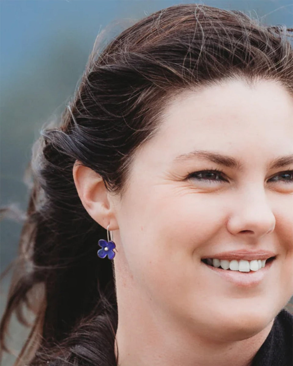 Close-up of a woman wearing a blue earring with a blurred background