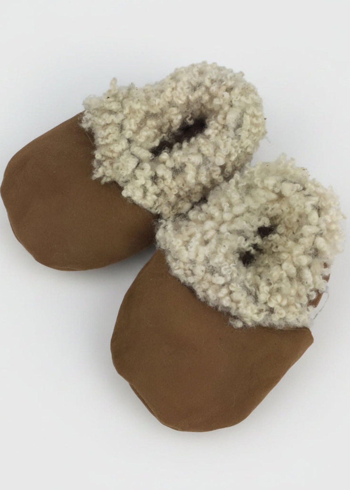 Pair of brown sheepskin slippers with white fuzzy trim on a white background