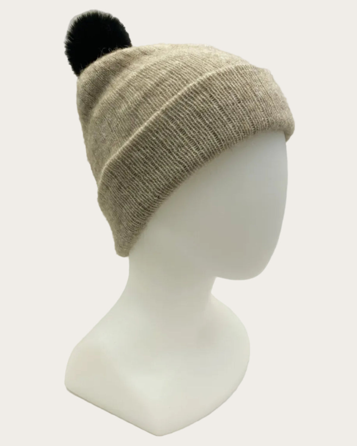 Beige possum merino beanie with a black pom-pom on a mannequin head against a light gray background