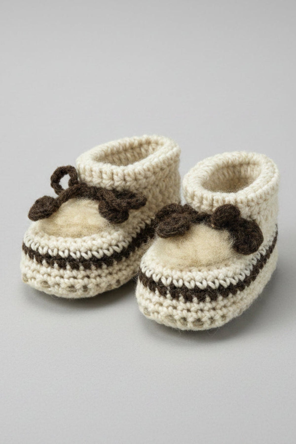 Pair of knitted baby booties with a bow on a white background