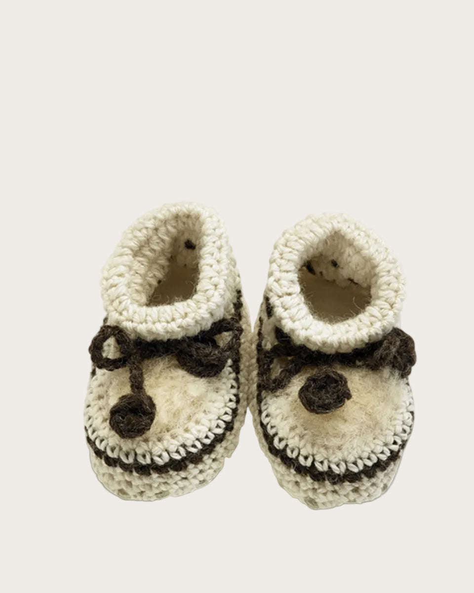 Pair of knitted baby booties with a bow on a white background