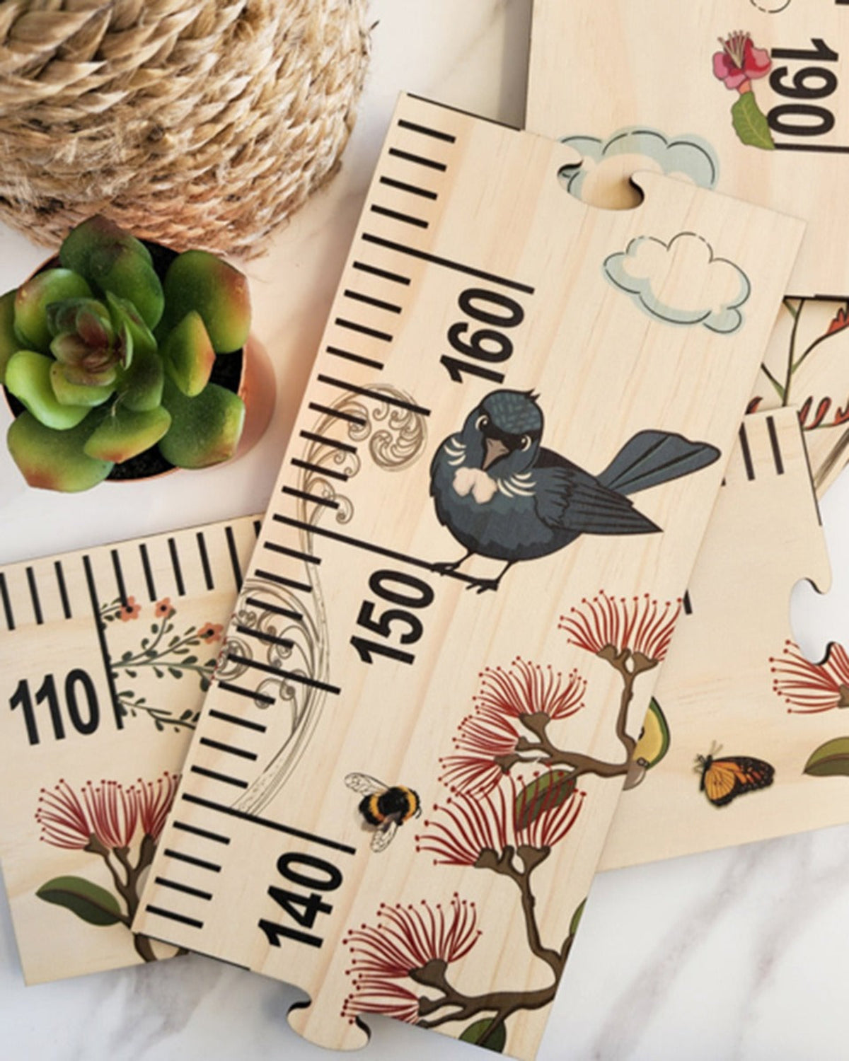 Wooden growth chart with bird and floral designs on a white surface.