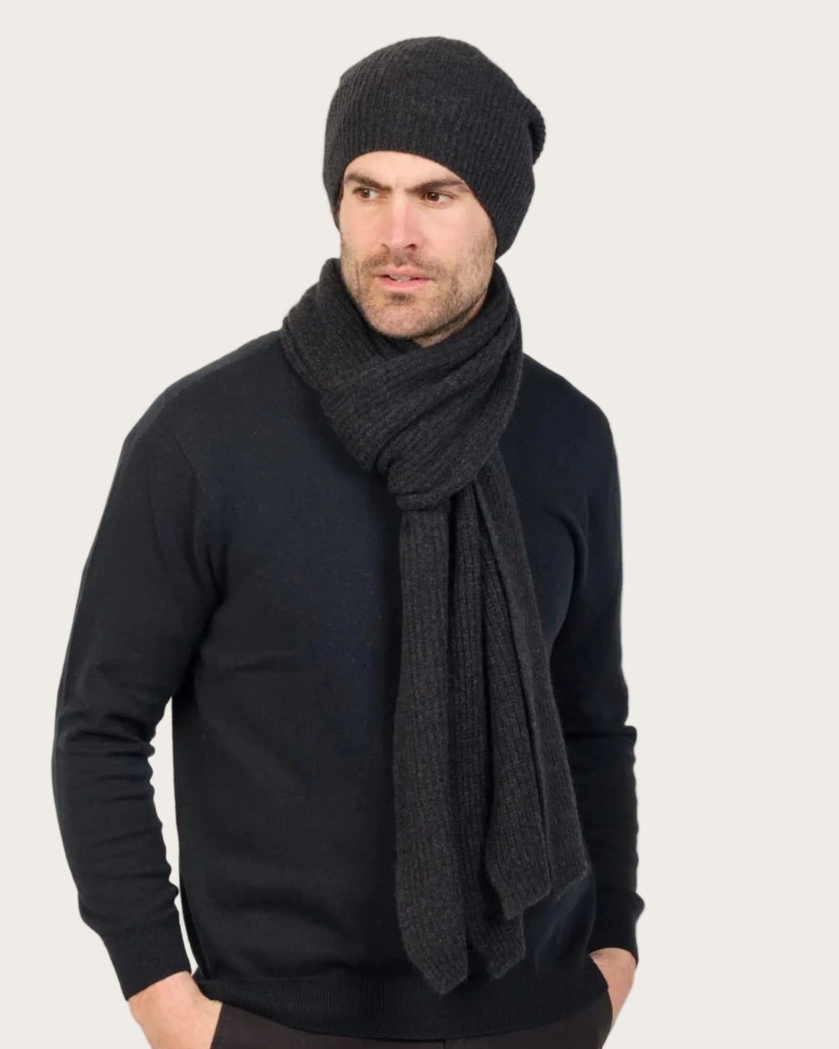 Man wearing a black knit beanie and scarf against a white background