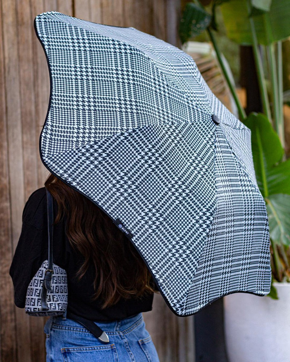 Person holding a black and white checkered umbrella with a blurred background