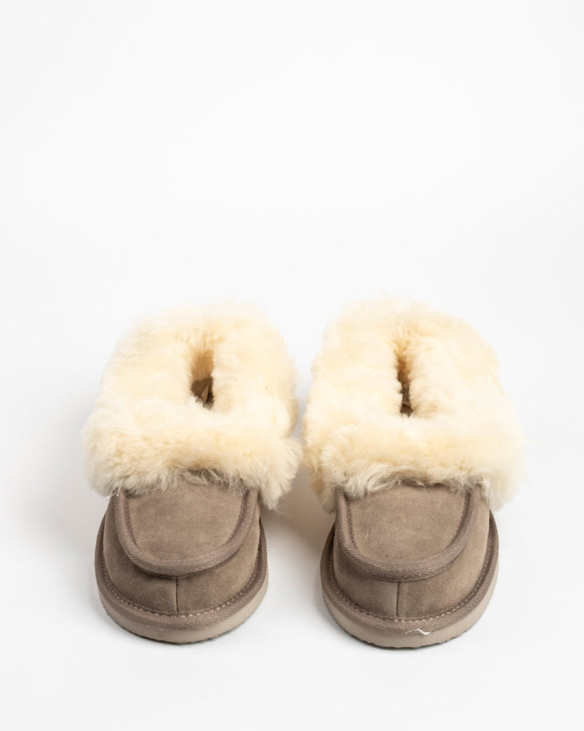 Pair of beige sheepskin suede boots with white fur lining on a white background