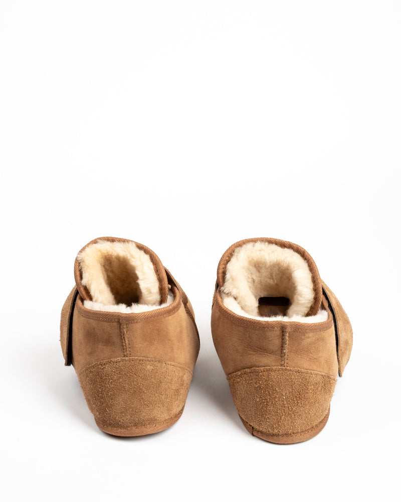 Pair of brown slippers with sheepskin lining on a white background